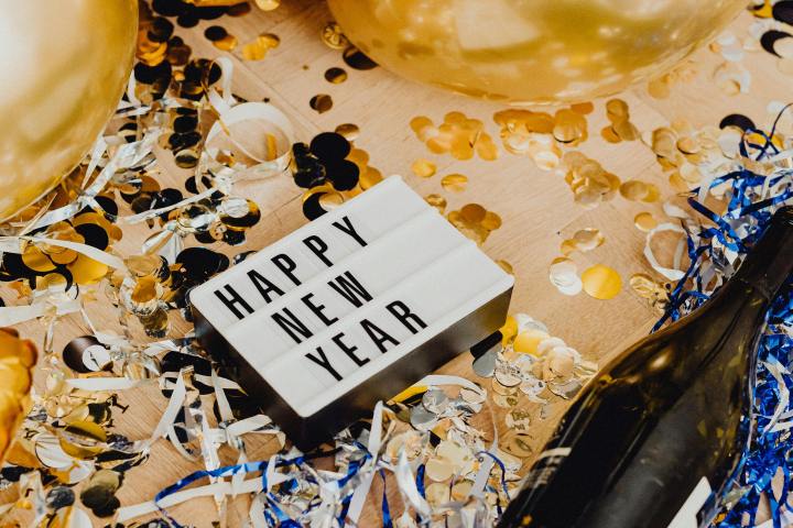 New Year celebration scene with balloons, confetti, and a lightbox displaying 'HAPPY NEW YEAR.'
