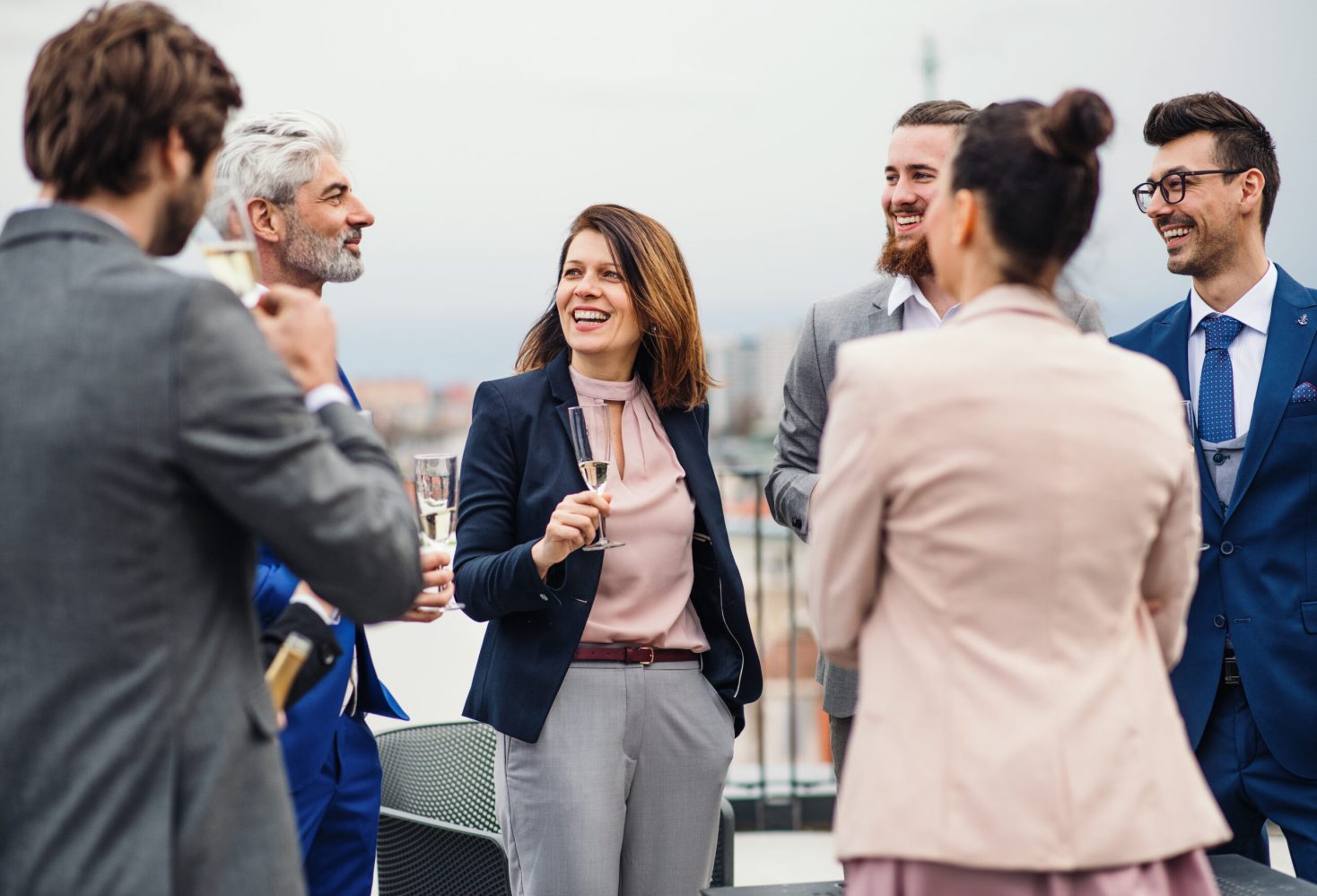 group of professionally dressed adults socializing outdoors with champagne during a corporate event on a boat