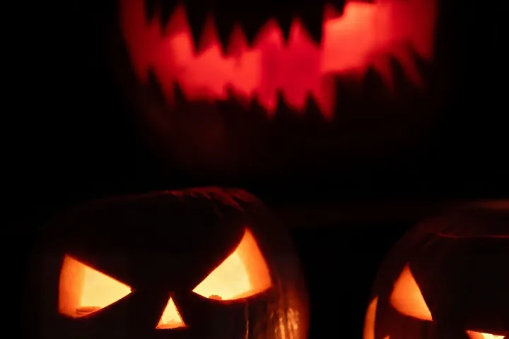 Three glowing carved pumpkins with menacing faces against a dark background.